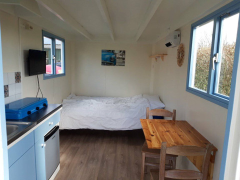 Interior de Pipowagen Snuitje en Camping De Gouwe Stek, Países Bajos, con cama, mesa y cocina.