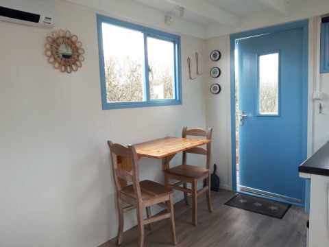 Acogedor comedor con mesa y dos sillas de madera en Pipowagen Snuitje de Camping De Gouwe Stek, Países Bajos.