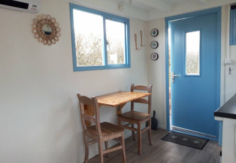 Acogedor comedor con mesa y dos sillas de madera en Pipowagen Snuitje de Camping De Gouwe Stek, Países Bajos.