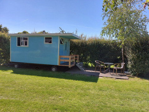 Cabaña azul móvil con porche y muebles de exterior en Pipowagen Snuitje, Camping De Gouwe Stek, Países Bajos