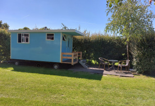 Cabaña azul móvil con porche y muebles de exterior en Pipowagen Snuitje, Camping De Gouwe Stek, Países Bajos