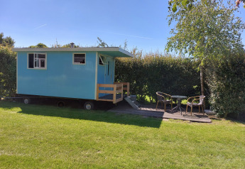 Cabaña azul móvil con porche y muebles de exterior en Pipowagen Snuitje, Camping De Gouwe Stek, Países Bajos
