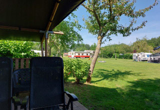 Vista desde la tienda Safari Kievit en Camping De Gouwe Stek, Países Bajos, con sillas y campo verde.