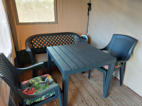 Sillas y mesa de plástico en la tienda Safari Kievit de Camping De Gouwe Stek, Países Bajos, suelo de madera