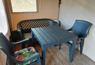 Sillas y mesa de plástico en la tienda Safari Kievit de Camping De Gouwe Stek, Países Bajos, suelo de madera