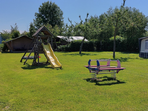 Parque infantil con tobogán y columpios en Safari tent Kievit en Camping De Gouwe Stek en Países Bajos.