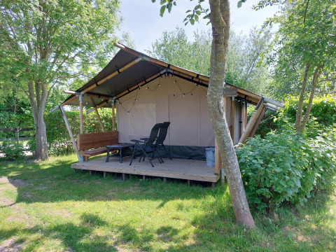 Tienda safari Kievit en Camping De Gouwe Stek, Países Bajos, rodeada de árboles y naturaleza verde.