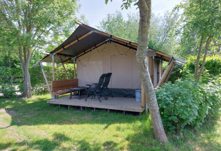 Tienda safari Kievit en Camping De Gouwe Stek, Países Bajos, rodeada de árboles y naturaleza verde.