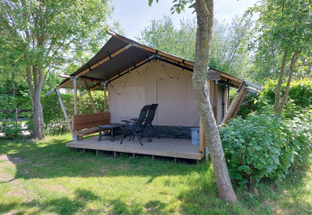 Safari tent Kievit at Camping De Gouwe Stek in the Netherlands, set among lush trees and greenery.