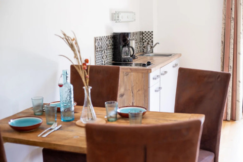 Mesa de comedor y pequeña cocina en alojamiento glamping de un parque vacacional, con cafetera.