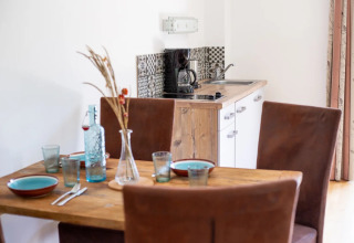 Eettafel en compacte kitchenette in een glampingverblijf op een vakantiepark met koffiemachine.