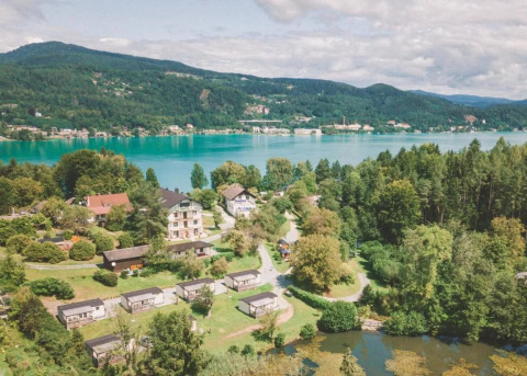 Vakantiepark met glampinghutten aan een meer, omringd door bos, bergen en een prachtig landschap.