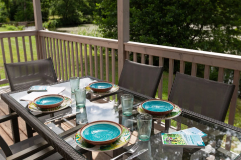 Table à manger extérieure dressée pour quatre dans un parc de vacances glamping, avec assiettes colorées.