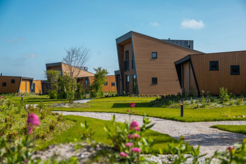 Parque vacacional moderno con alojamientos glamping de diseño único y senderos rodeados de naturaleza verde.