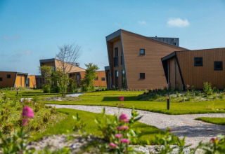 Moderne Ferienanlage mit ungewöhnlich geformten Glamping-Hütten und gepflegten Wegen im Grünen.