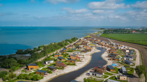 Vakantiepark met glampingaccommodaties aan een meer, omgeven door natuur en water.