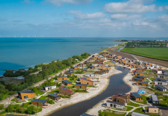 Vakantiepark met glamping verblijven bij een meer, omgeven door natuur, water en groen.