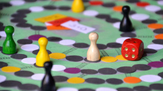 Juego de mesa con fichas de colores y un dado rojo sobre el tablero, ideal para una noche divertida.