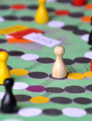 Board game scene with colorful pawns and a red die on the game board, set for a fun game night.