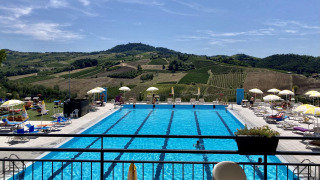 Piscina exterior en el parque vacacional Per Amore del Vino en Lombardía, Italia, rodeada de viñedos.