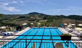 Piscina exterior en el parque vacacional Per Amore del Vino en Lombardía, Italia, rodeada de viñedos.