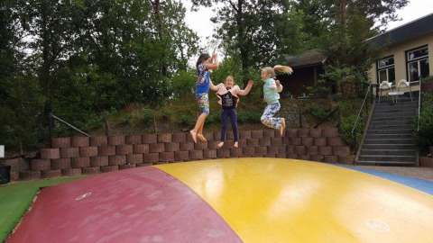 Tres niños saltan sobre una gran almohadilla inflable en Camping Roland, parque vacacional en Limburg, Países Bajos.