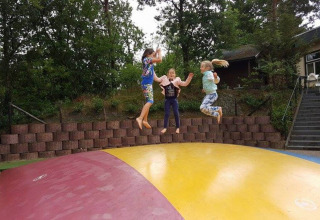 Tre bambini saltano su un grande cuscino gonfiabile al Camping Roland, parco vacanze in Limburg, Paesi Bassi.