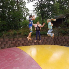Tres niños saltan sobre una gran almohadilla inflable en Camping Roland, parque vacacional en Limburg, Países Bajos.
