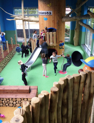 Parque infantil interior con niños, tobogán y troncos en Camping Roland, un parque vacacional en Limburg.