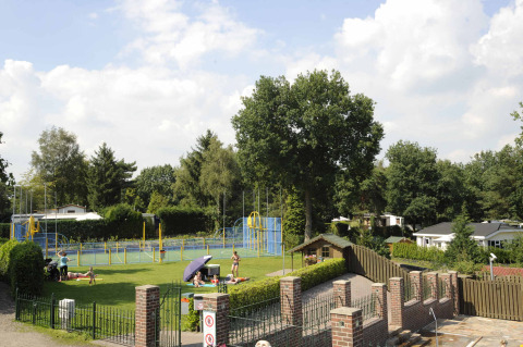 Udsigt over Camping Rolands grønne område med legeplads, familieaktiviteter og hytter i Limburg, Holland.