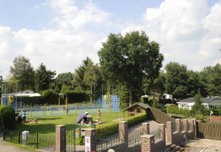 Udsigt over Camping Rolands grønne område med legeplads, familieaktiviteter og hytter i Limburg, Holland.