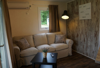 Accogliente soggiorno nella Lodge di Camping Roland, Paesi Bassi, con divano e decorazione murale.