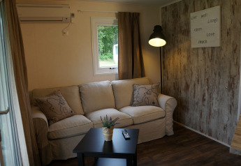 Accogliente soggiorno nella Lodge di Camping Roland, Paesi Bassi, con divano e decorazione murale.