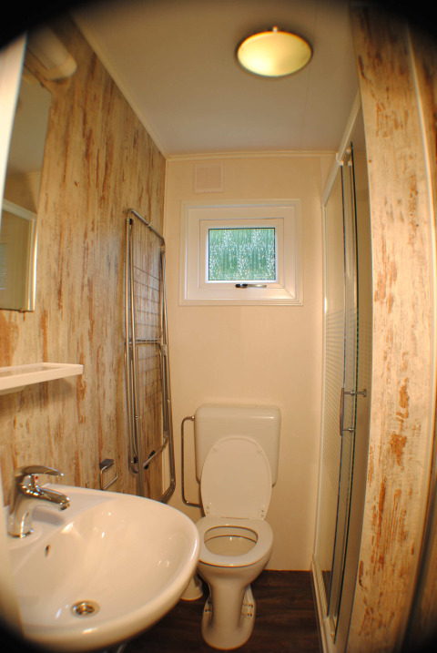 Petite salle de bain dans une lodge à Camping Roland, Pays-Bas, avec toilettes, lavabo et douche.