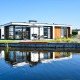 Moderne Villa Nautica ved MarinaPark Residentie Nieuw Loosdrecht i Holland, spejler sig i roligt vand.