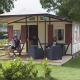Familie sidder udenfor en lodge ved Camping Roland, omgivet af grønt græs og træer i Holland.