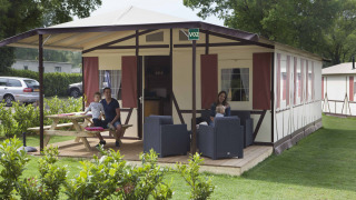 Familie entspannt auf der Veranda vom Vakwerktent-Lodge auf Camping Roland, Niederlande.