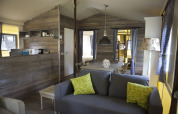 Intérieur chaleureux d’un lodge en bois à Vakwerktent, Camping Roland, Pays-Bas, avec canapé et salle à manger.