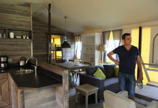Uomo in piedi nel soggiorno di un'accogliente lodge a Vakwerktent presso Camping Roland, Paesi Bassi.