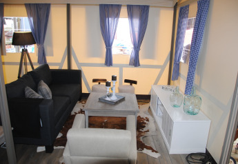 Stue i Vakwerktent på Camping Roland, Holland, med moderne møbler og blå-hvide gardiner.