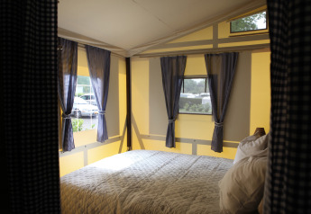 Gemütlicher Innenraum einer Vakwerktent-Lodge mit karierten Vorhängen auf Camping Roland in den Niederlanden.