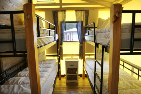 Chambre avec quatre lits superposés et bois dans la lodge Vakwerktent au Camping Roland, Pays-Bas, vue sur fenêtre.