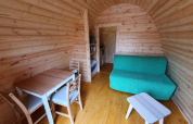 Indvendigt billede af et lille træhus, Pod, med spisebord, sofa og bord på Camping Roland, Holland.