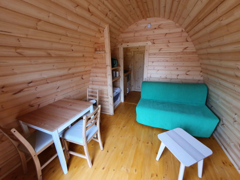 Interior de una pequeña casa de madera, Pod, con mesa de comedor, sofá y mesa en Camping Roland, Países Bajos.