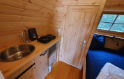 Indvendigt billede af et lille træpod-hus med mini køkken og seng i Camping Roland, Nederlandene.