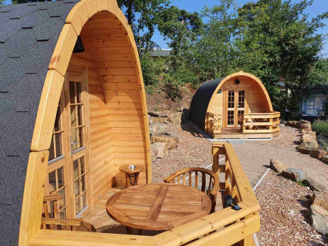 Cabines pod en bois avec terrasses au Camping Roland aux Pays-Bas, entourées de verdure et d’arbres.