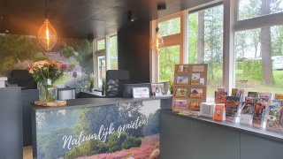 Recepción del Camping het Horstmannsbos en Drenthe, Países Bajos, con folletos y decoración floral.