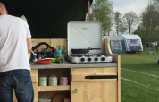 Cocina exterior en el Stoere Safari tent de Camping de Berghoeve, Países Bajos, con hombre cocinando.