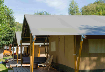 Safaritelt på Camping Val d'Or i Luxembourg, træterrasse og stole under en blå himmel.