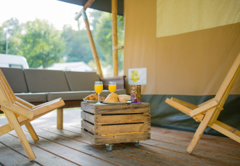 Gemütlicher Außenbereich mit Holzmöbeln und Frühstück im Safarizelt auf Camping Val d'Or, Luxemburg.